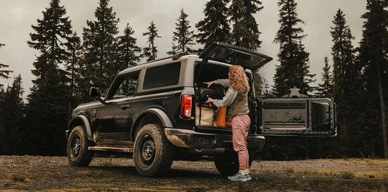 A woman loading bags in to the back of a 2025 Ford Bronco.