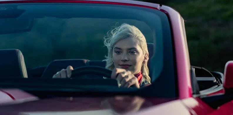 A photo of a woman driving a 2026 Ford Mustang.