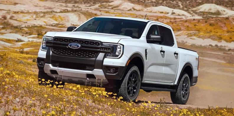 A white 2025 Ford Ranger off-roading up a hill.