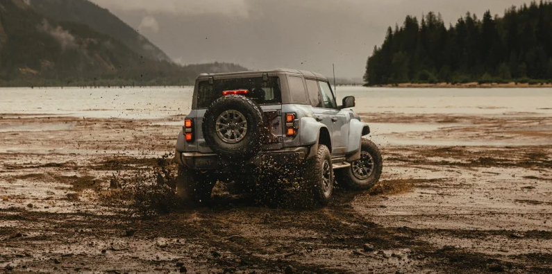 A 2025 Ford Bronco off-roading through some mud.