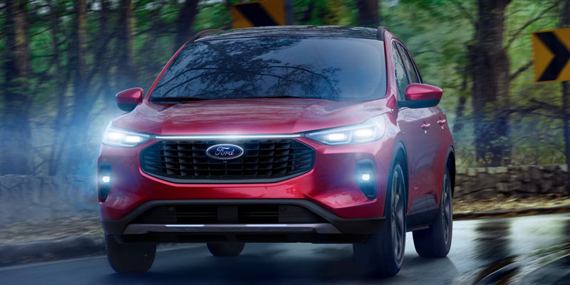 2026 Red Ford Escape cruising on road middle in forest